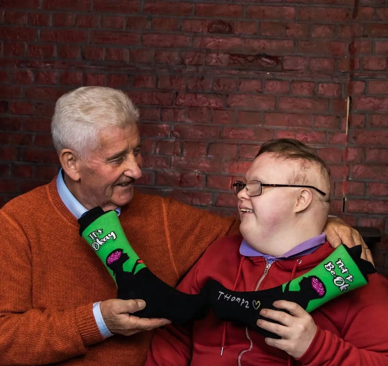 Thomas y su padre con un par de calcetines que dicen: "Está bien no estar bien".