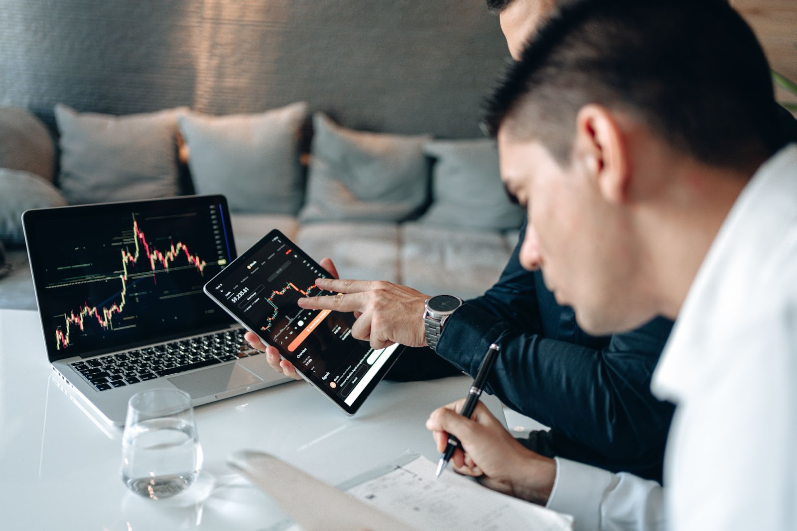 Two Men Discussing Graphs and Data on Computer Screens