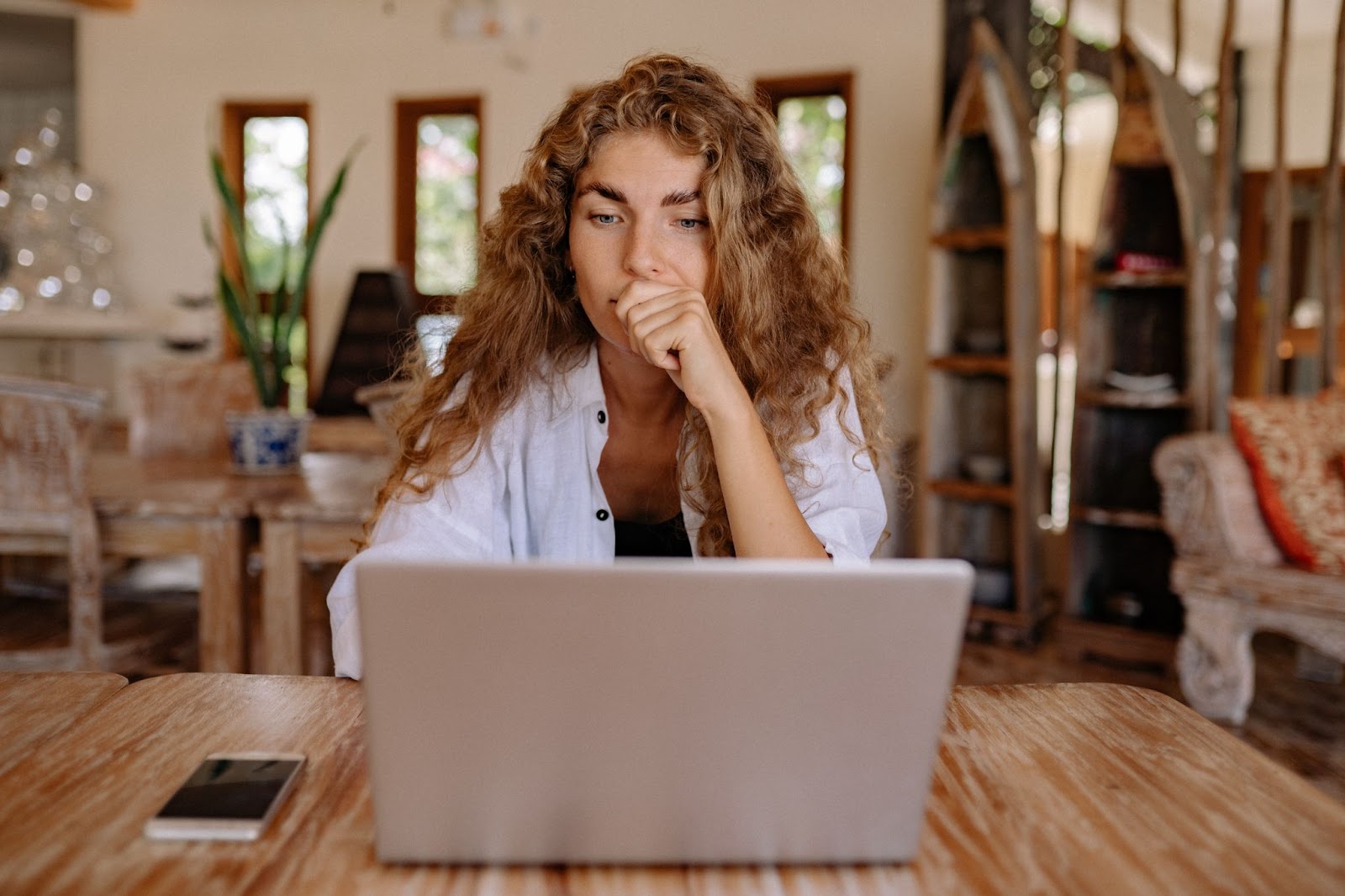  Thinking women sitting behind laptop screen