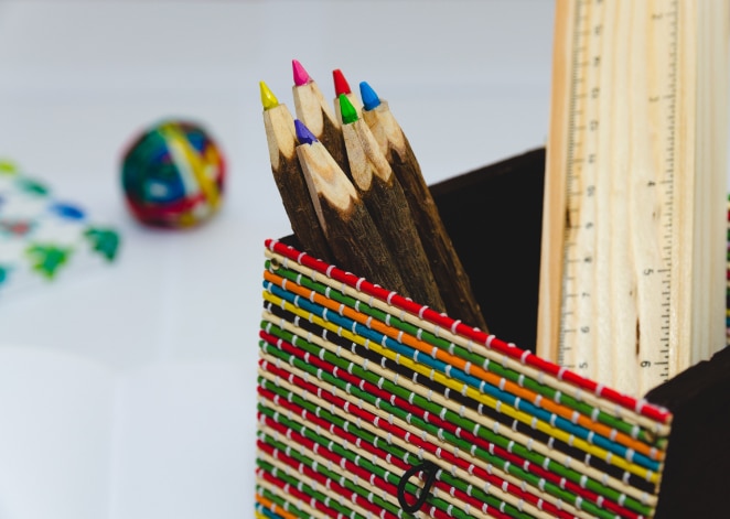 crayons de couleur dans un porte-crayon coloré aux côtés de règles et d'une balle élastique