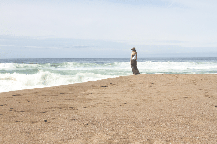 海を見渡す浜辺に立つ女性