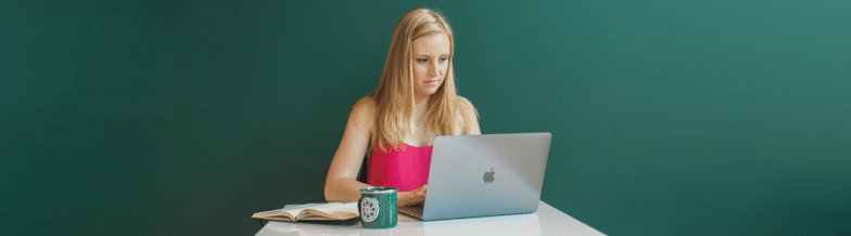 femme écrivant des idées de marketing de contenu dans un ordinateur portable avec un ordinateur portable et une tasse à volant à proximité