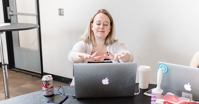 femme avec les mains tendues sur un ordinateur portable et un café au bureau