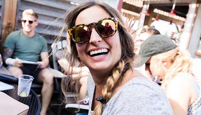 mise en page par le bloc du concepteur du volant femme dans des lunettes de soleil réfléchissantes riant entre amis à l'extérieur