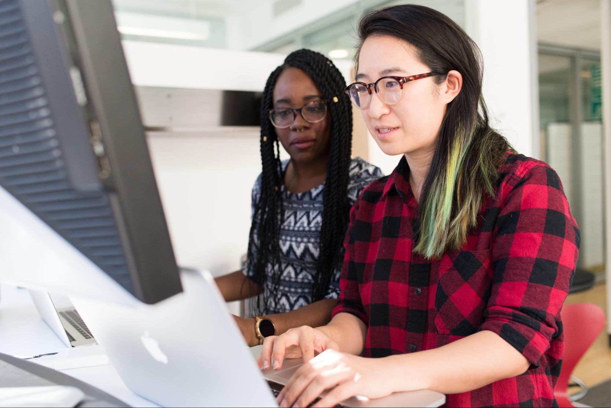 dua pengembang wanita bekerja di komputer desktop