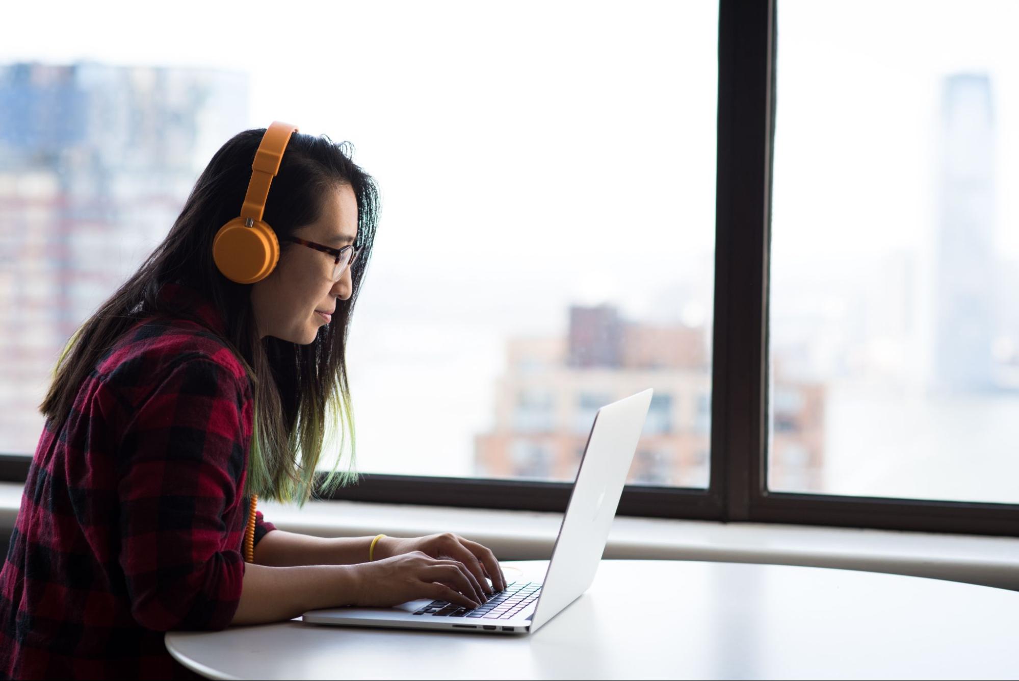 wanita bekerja di laptop, memakai headphone