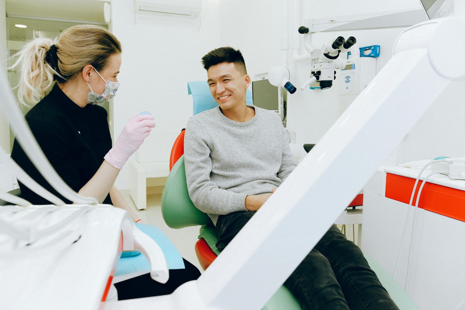 Homem na cadeira do dentista, conversando confortavelmente com seu dentista.