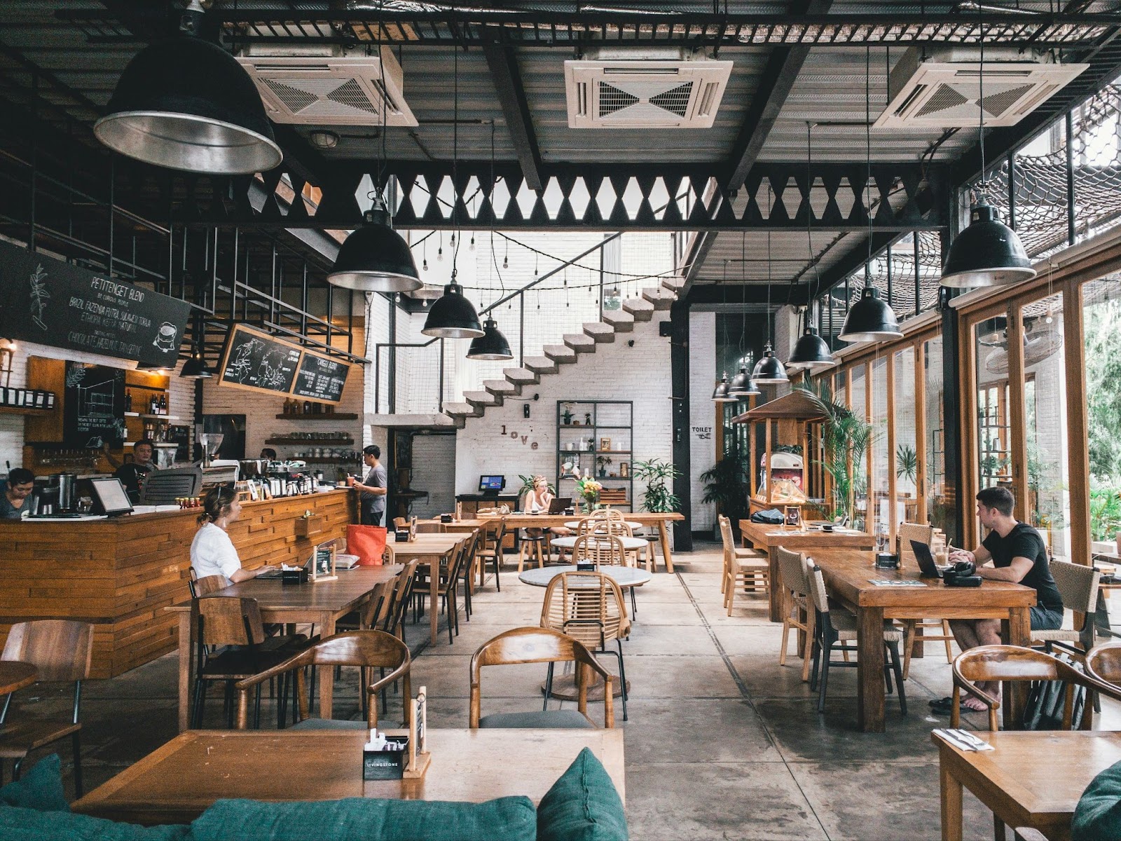 Una gran cafetería rústica con solo unas pocas personas trabajando en sus computadoras portátiles y tomando café.