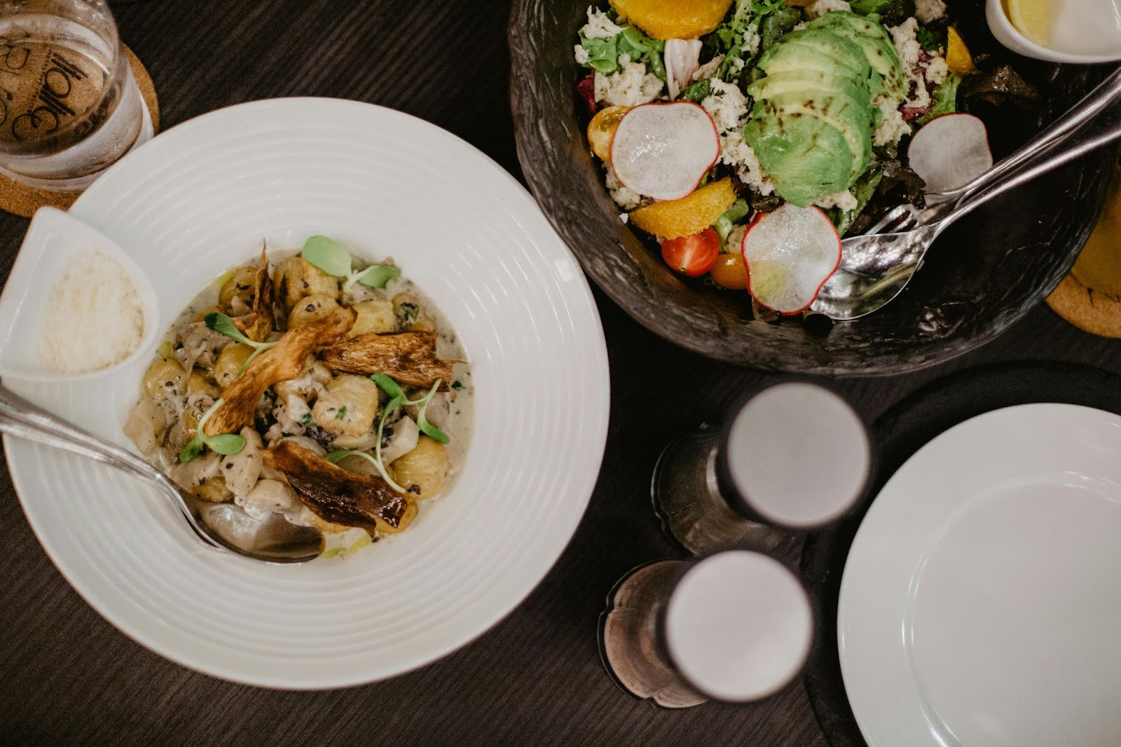 Uma refeição em restaurante rústico de estilo fazenda - sopa e salada com água, sal e pimenta.