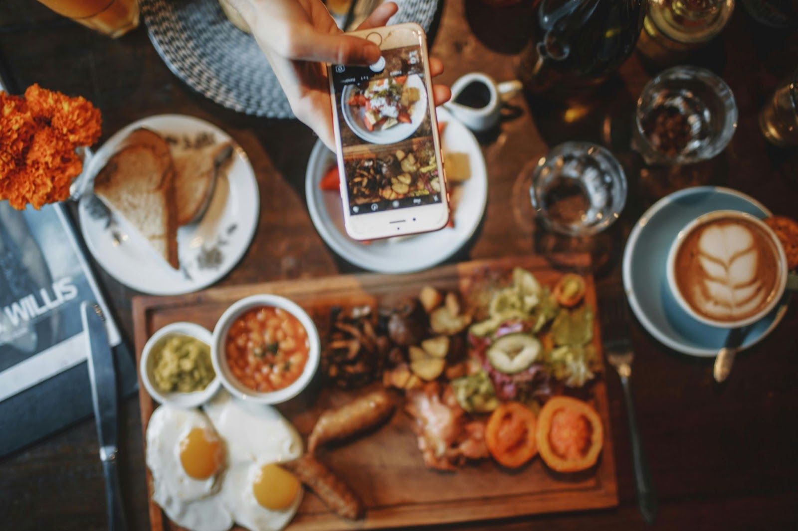 Personne utilisant un téléphone intelligent pour prendre une photo de la nourriture du petit-déjeuner et du café dans un café rustique.