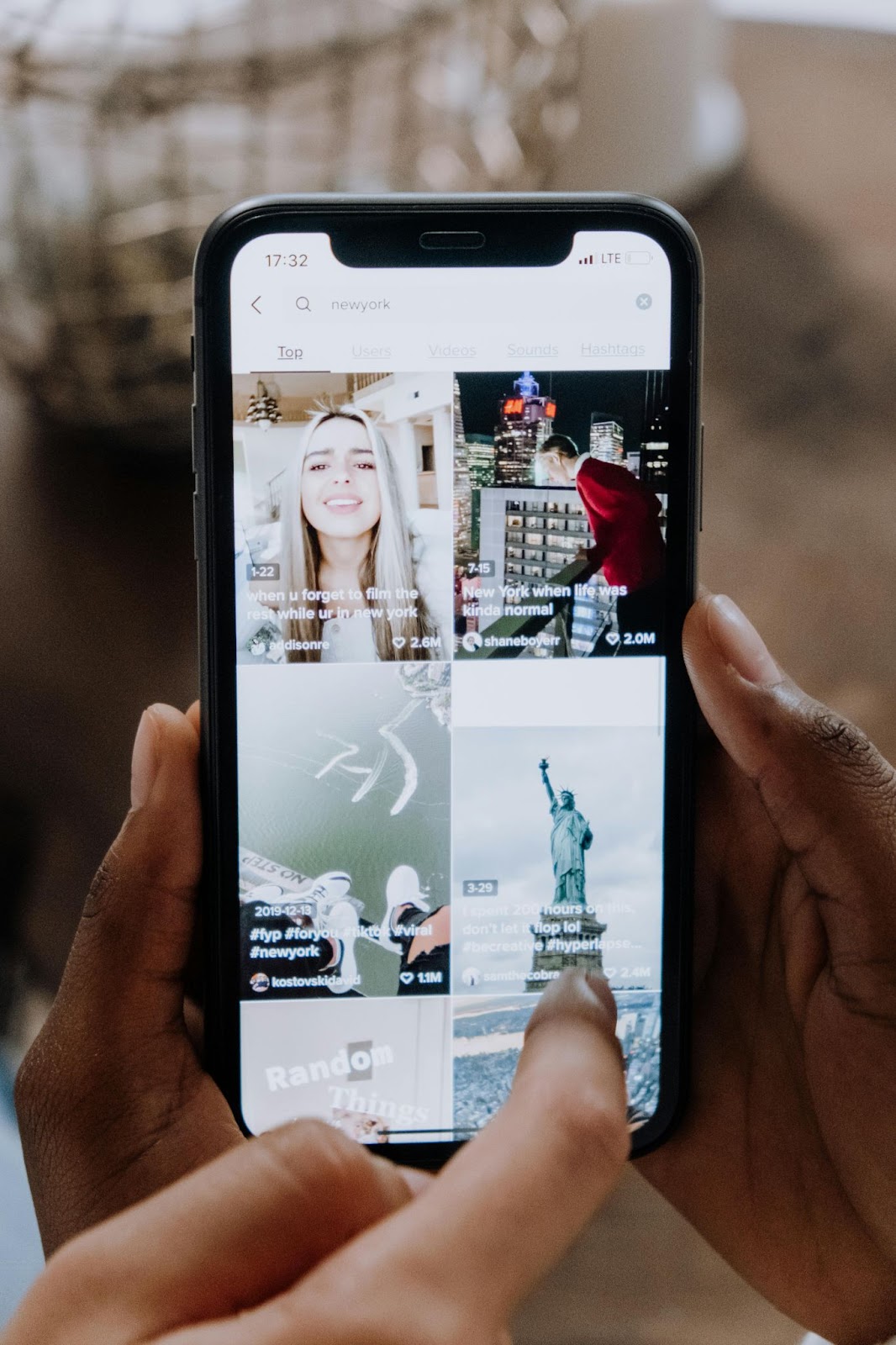 Zwei Hände halten eine Social-Media-Anwendung auf einem Smartphone und zeigen darauf.