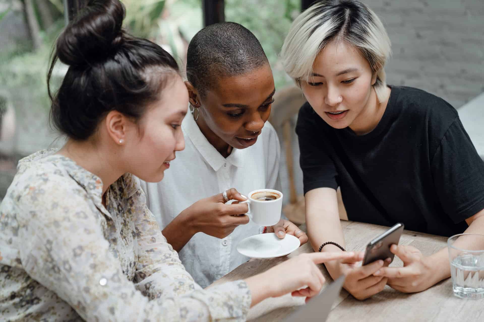 携帯電話を見ている 3 人の女の子