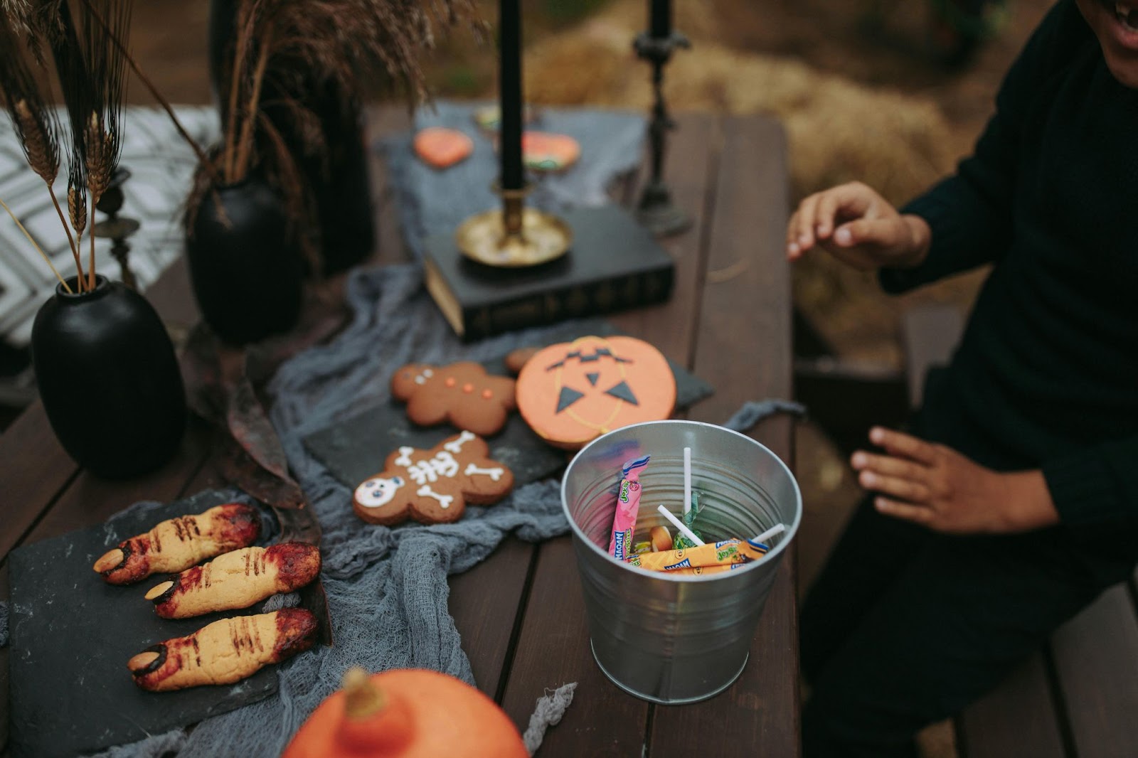 Biscoitos temáticos de Halloween sendo decorados em um espaço externo rústico, semelhante a um celeiro.