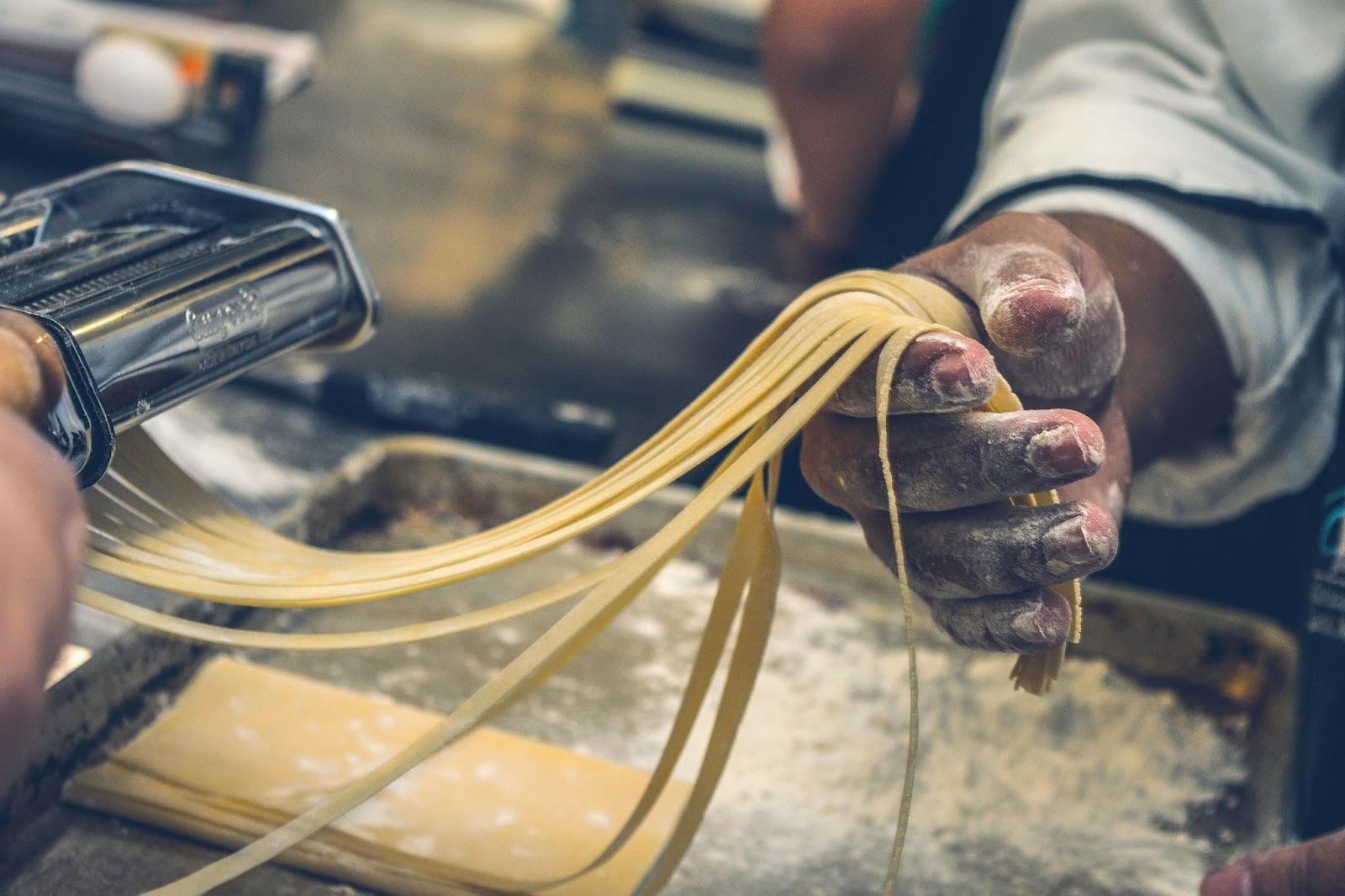 キッチンでパスタを作る男性、手のクローズアップ